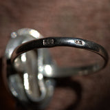 Close-up of a silver ring with '925' stamp on a brown background