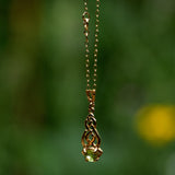 Gold Celtic pendant with a green Peridot gemstone on a blurred green background