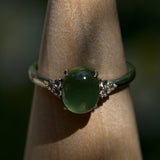 Green gemstone ring on a wooden stand with a blurred background