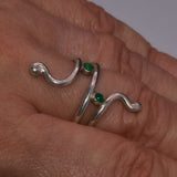 Solid silver ring with green Onyx gemstones on a person's finger against a neutral background