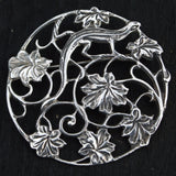 silver round brooch featuring lizard and leaves