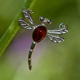 Solid silver dragonfly brooch with an Amber stone on a green  background